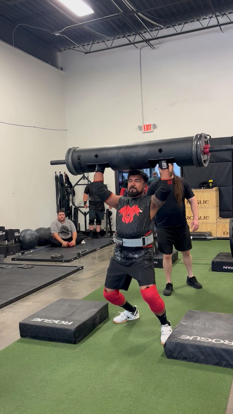 Strongman competitor holding a log overhead at Per Aspera Strength