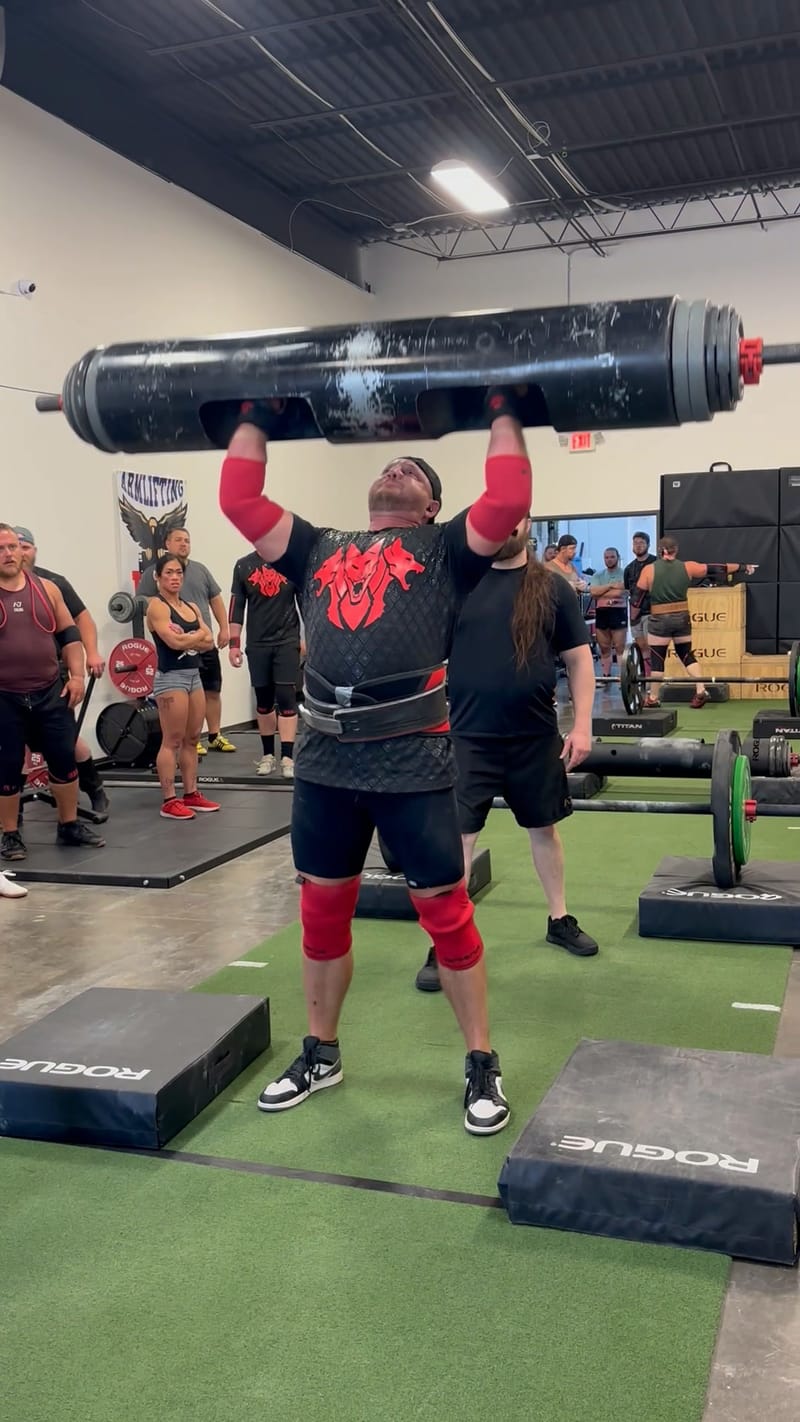 Competitor locking out a log press at the Midsummer Melee strongman competition