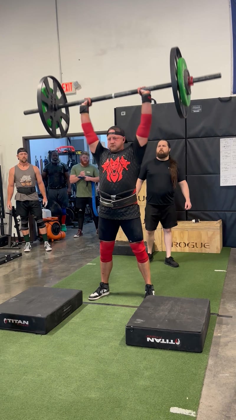 Competitor pressing a loaded barbell overhead at the Midsummer Melee