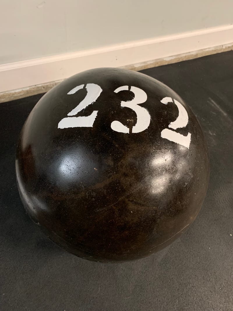 232 lb atlas stone in a black finish with a white stenciled number